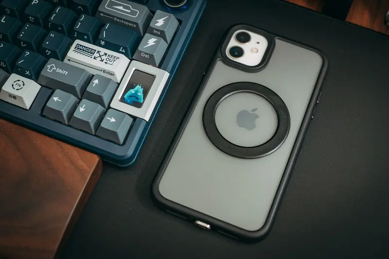 A close-up of a custom keyboard with keycaps and a smartphone on a sleek desk setup