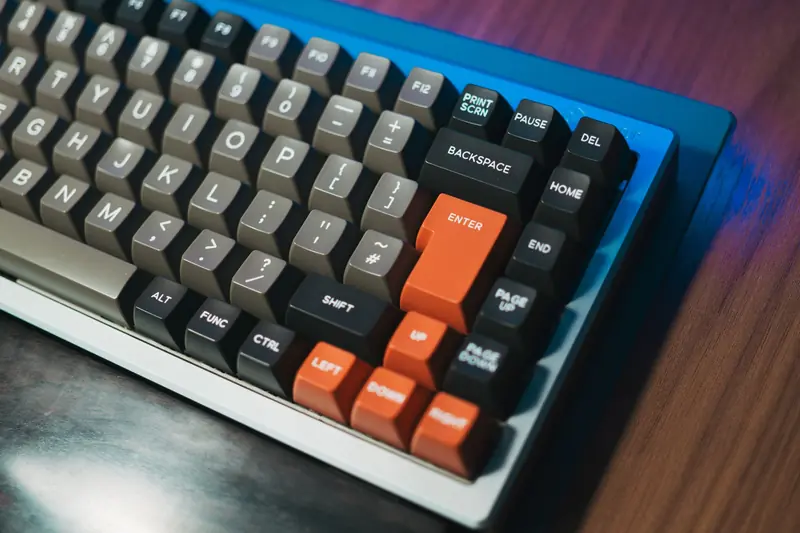 Detailed close-up of a mechanical keyboard with colored keycaps on a wooden desk. Ideal for tech enthusiasts