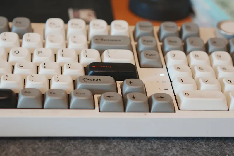 A detailed image of a mechanical keyboard with gray and white keys on a workspace