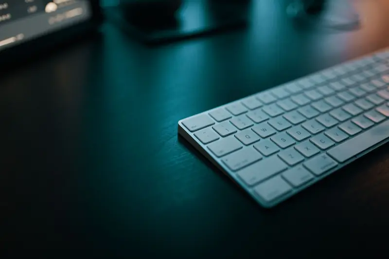 Sleek white keyboard on a dark desk, ideal for modern workspace themes