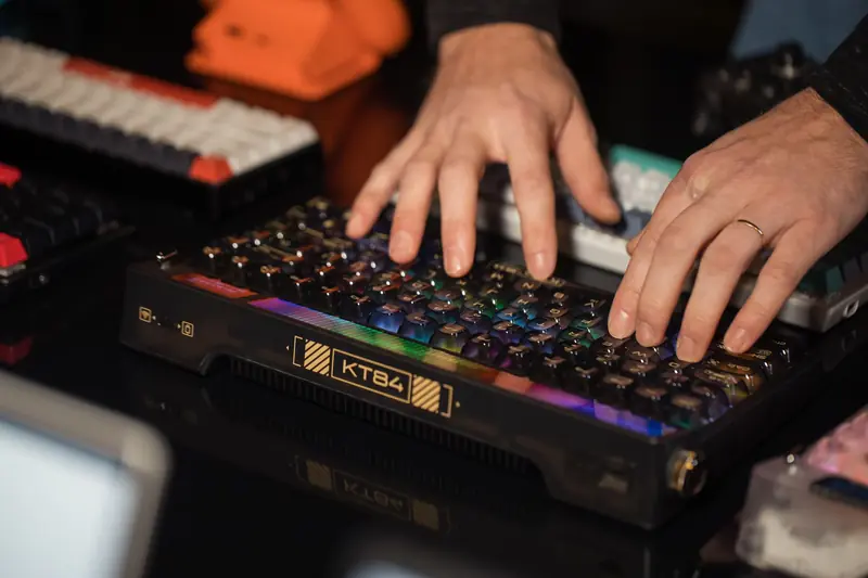 Hands typing on an RGB mechanical keyboard with colorful lights on a desk, creating a vibrant tech scene