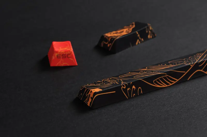 Stylish close-up of black and orange keyboard keycaps with intricate patterns, showcasing a modern artistic design
