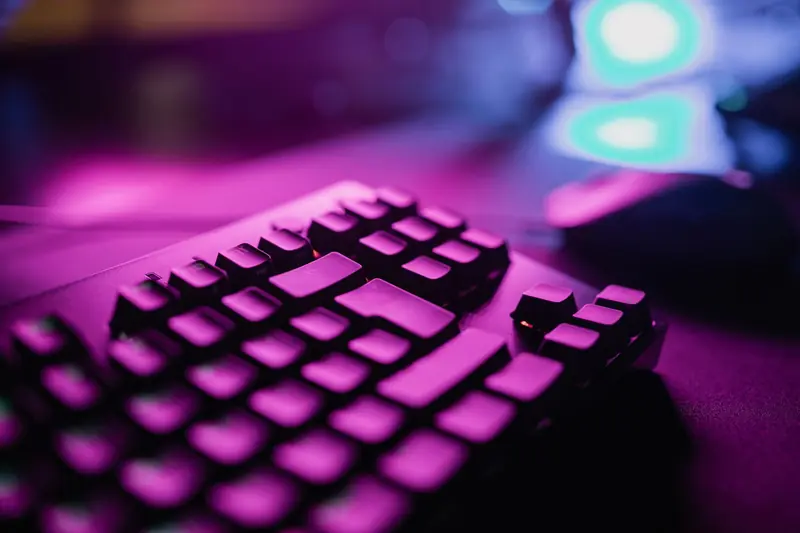A close-up view of an RGB backlit gaming keyboard with a vibrant purple glow, perfect for tech and gaming enthusiasts