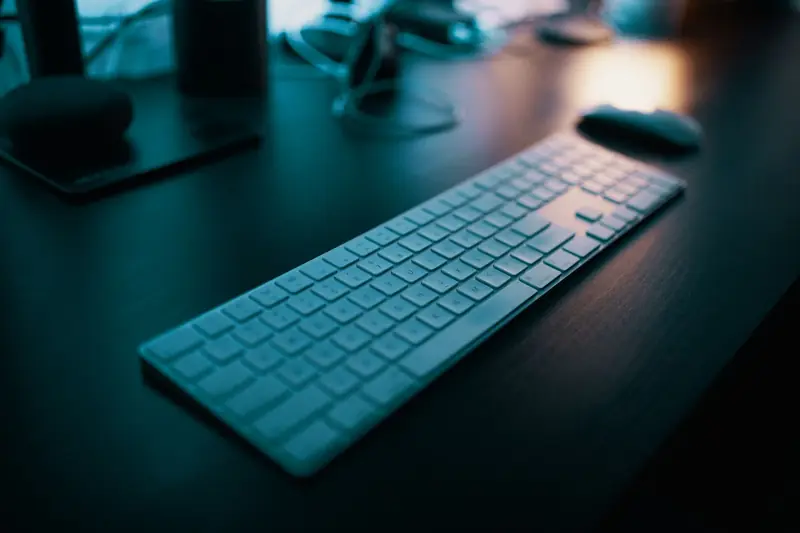 A modern wireless keyboard placed on a sleek desk, illuminated by ambient lighting in a tech-savvy office setting